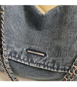 Close-up of blue denim tote bag with silver chain strap and frayed edge detail