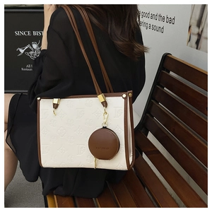 Detail of white embossed tote bag with brown trim and round coin purse attachment