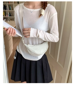Sac demi-lune en nylon blanc cassé porté avec une jupe plissée décontractée