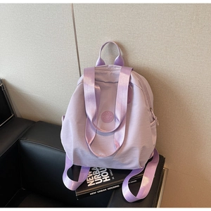 Detail eines hellvioletten Nylon-Rucksacks mit breiten Griffen auf schwarzem Sofa