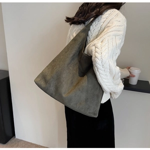 Detail shot of green suede tote bag with matte texture on white knit sweater