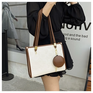 Chic tote bag featuring white embossed floral patterns and brown leather strap detail