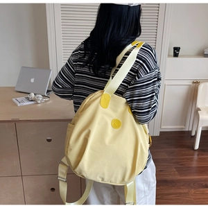 Detail eines gelben Rucksacks mit großem Fassungsvermögen und rundem Markenlogo