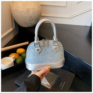 Détail du sac coquillage en denim bleu avec strass brillants et finitions en cuir argenté