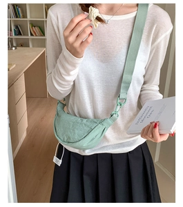 Sac bandoulière demi-lune en nylon vert menthe porté par un mannequin en intérieur