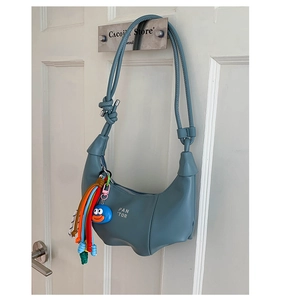 Detail of Morandi blue dumpling bag with colorful rope tassel and cartoon pendant charms