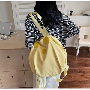 Detail eines leuchtend gelben Nylon-Rucksacks mit glatter Textur und breiten Trägern