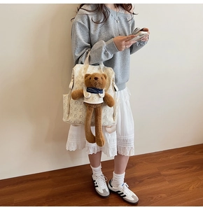 Detail of printed canvas backpack with a large brown plush long-legged bear pendant