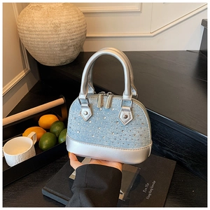 Détail de mini sac coquillage en denim bleu clair avec bordure argentée et strass brillants