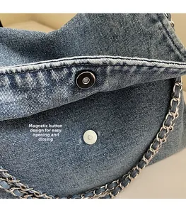 Detail of magnetic snap closure and denim texture on large tote bag with chain strap