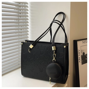 Detail of black embossed tote bag with gold hardware and matching coin purse pendant