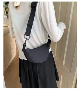 Détail d'un sac bandoulière demi-lune en nylon noir avec large sangle sur le mannequin