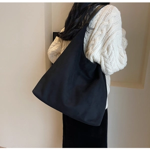 Close-up of the large black faux suede tote bag showing soft texture and drape style