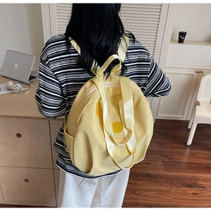 Detailansicht eines gelben Nylon-Rucksacks, getragen von einem Modell im Arbeitszimmer