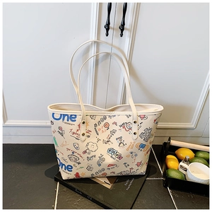 Détail d'un sac cabas en toile beige avec graffitis colorés et doubles bandoulières