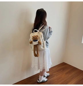 Close-up of children's white canvas backpack with bear prints and a plush bear doll accessory