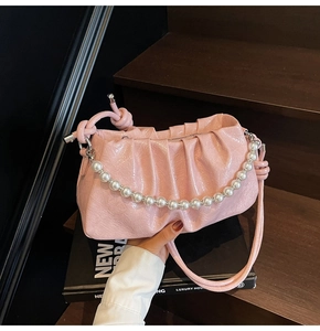 Dettaglio della borsa a nuvola rosa lucida con catena di perle e tracolla sottile