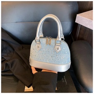 Gros plan détaillé du sac coquillage en denim bleu avec strass argentés et accents métal