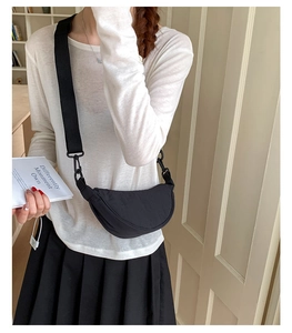 Détail du sac demi-lune en nylon noir minimaliste avec bandoulière large sur le mannequin