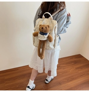 Close-up of white printed backpack featuring a cute plush bear and Lazy Bear pattern