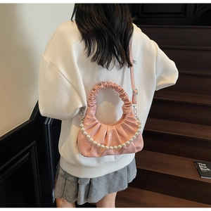 Pink pleated cloud bag with pearl chain detail and adjustable strap on a model