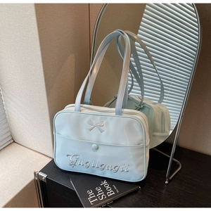 Detailed view of light blue shoulder bag with bow embroidery and metallic zipper