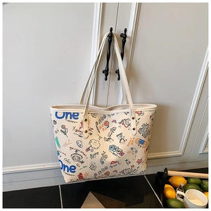 Detail of large tote bag with colorful cartoon graffiti on off-white canvas surface