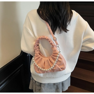 Dettaglio della borsa a nuvola plissettata rosa con catena di perle indossata a tracolla