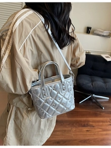Silberne Stepp-Beuteltasche mit Nieten-Details am Modell in lässiger Umgebung