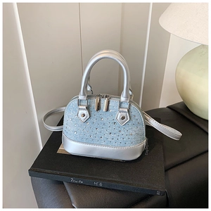 Détail du sac dôme en denim bleu clair et cuir argenté avec des strass étincelants