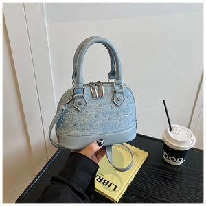 Détails d'un sac coquillage bleu clair avec strass et fermeture éclair argentée