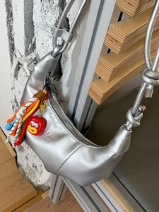 Silver metallic crescent dumpling bag with colorful rope charm and cartoon pendant