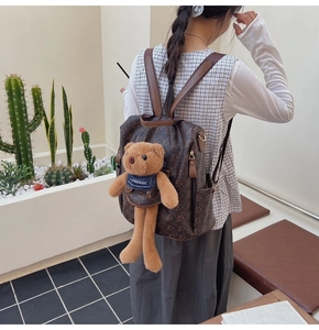 Close-up of a vintage brown backpack with bear prints and a cute plush teddy bear charm