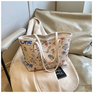 Détail du sac cabas blanc avec des imprimés graffiti colorés sur surface en cuir