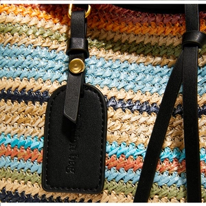 Détail macro du sac cabas en paille tissée multicolore avec poignée en cuir noir et rivet