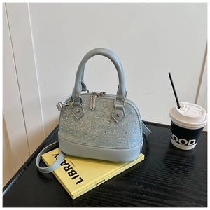 Détail du sac coquille bleu clair avec strass argentés sur denim et cuir élégant