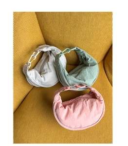 Vue détaillée de sacs demi-lune en nylon beige, vert et rose sur tissu en velours jaune