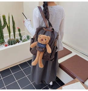 Outdoor view of a vintage printed backpack featuring a large 3D teddy bear charm