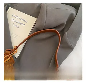 Détail des poignées en cuir marron sur un sac cabas d'été en paille tressée beige