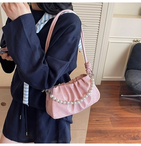 Dettaglio borsa nuvola rosa a pieghe con elegante catena di perle sulla spalla
