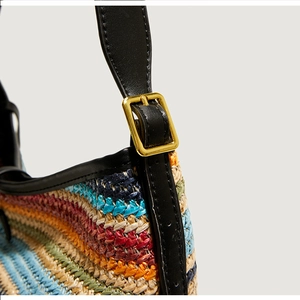Détail du sac bandoulière tissé coloré avec sangle en cuir noir et boucle dorée