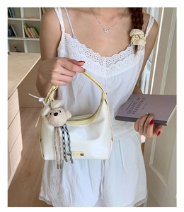 White hobo shoulder bag with yellow trim detail and cute teddy bear charm accessory
