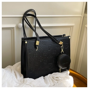 Close-up of black leather tote bag with FG flower embossing and fashion coin purse charm