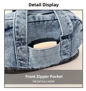 Detail view of denim handbag showing front zipper pocket and reinforced stitching