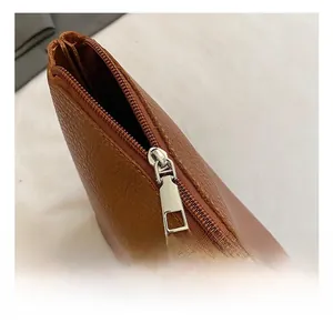 Détail de la fermeture éclair en métal argenté sur un sac en cuir marron à grain lychee