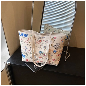 Détail de l'imprimé graffiti coloré et des anses en cuir sur le sac cabas blanc cassé