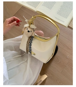 Detail of cream tote bag with yellow edges, featuring a cute plush dog pendant and tassel