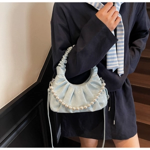 Borsa a nuvola plissettata azzurra con catena di perle indossata da una modella a tracolla