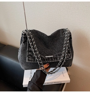 Detail of dark grey denim shoulder bag with double silver chain and washed texture