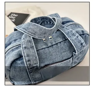 Detailed top view of the blue washed denim handbag featuring sturdy dual handles and zippers